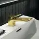Waschtischarmatur in brushed gold von Ideal Standard, mit flacher, rechteckiger Auslaufform und einfachem Bedienhebel. Montiert auf einem weißen Waschbecken.